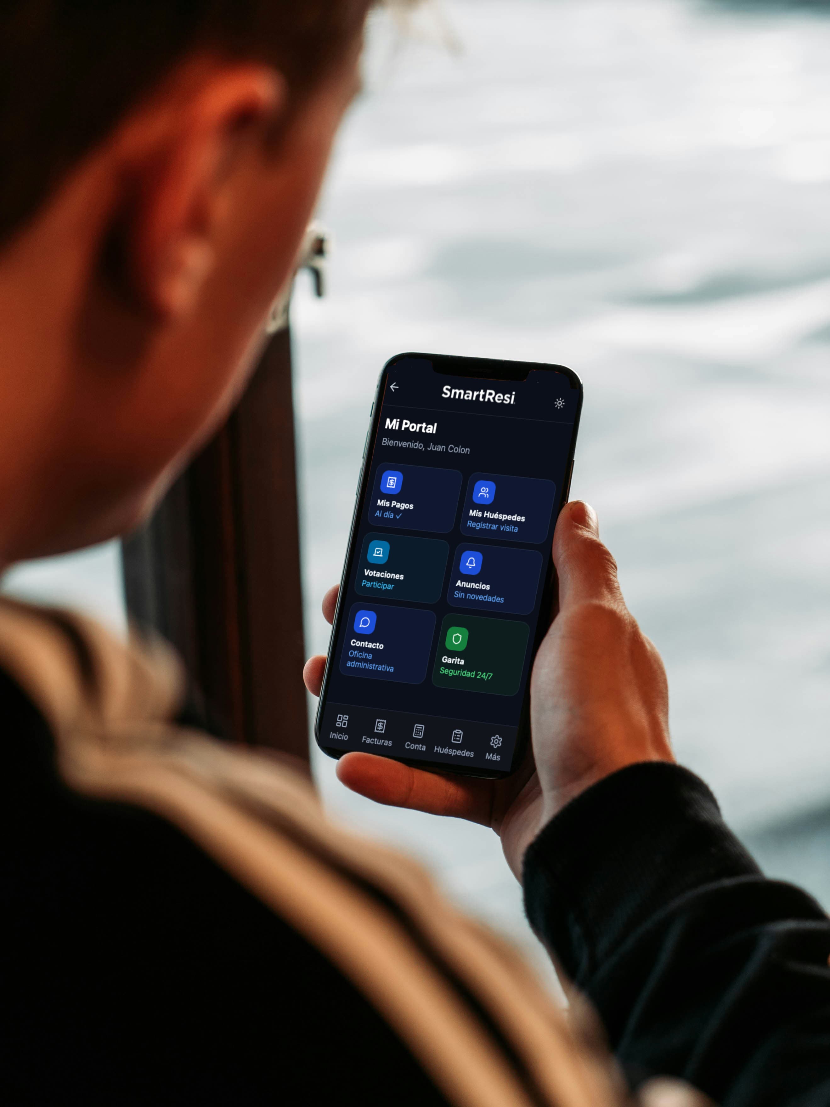 Persona usando un smartphone con la interfaz de la aplicación de gestión residencial SmartResi.